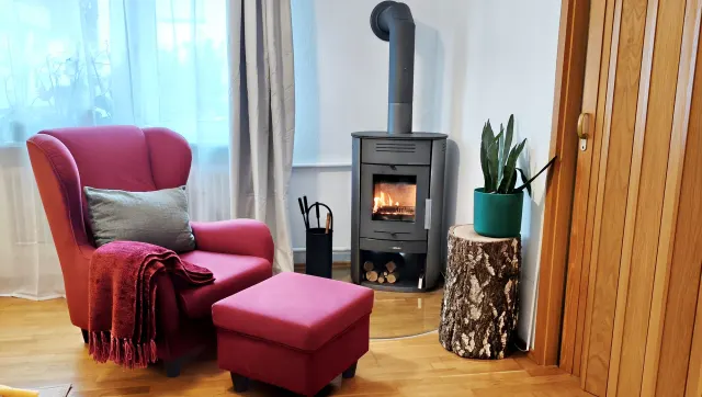 BookNoFees: casa de férias em Bensheim – Sala de estar com salamandra, poltrona cor-de-rosa e mesa de apoio feita de um tronco de árvore