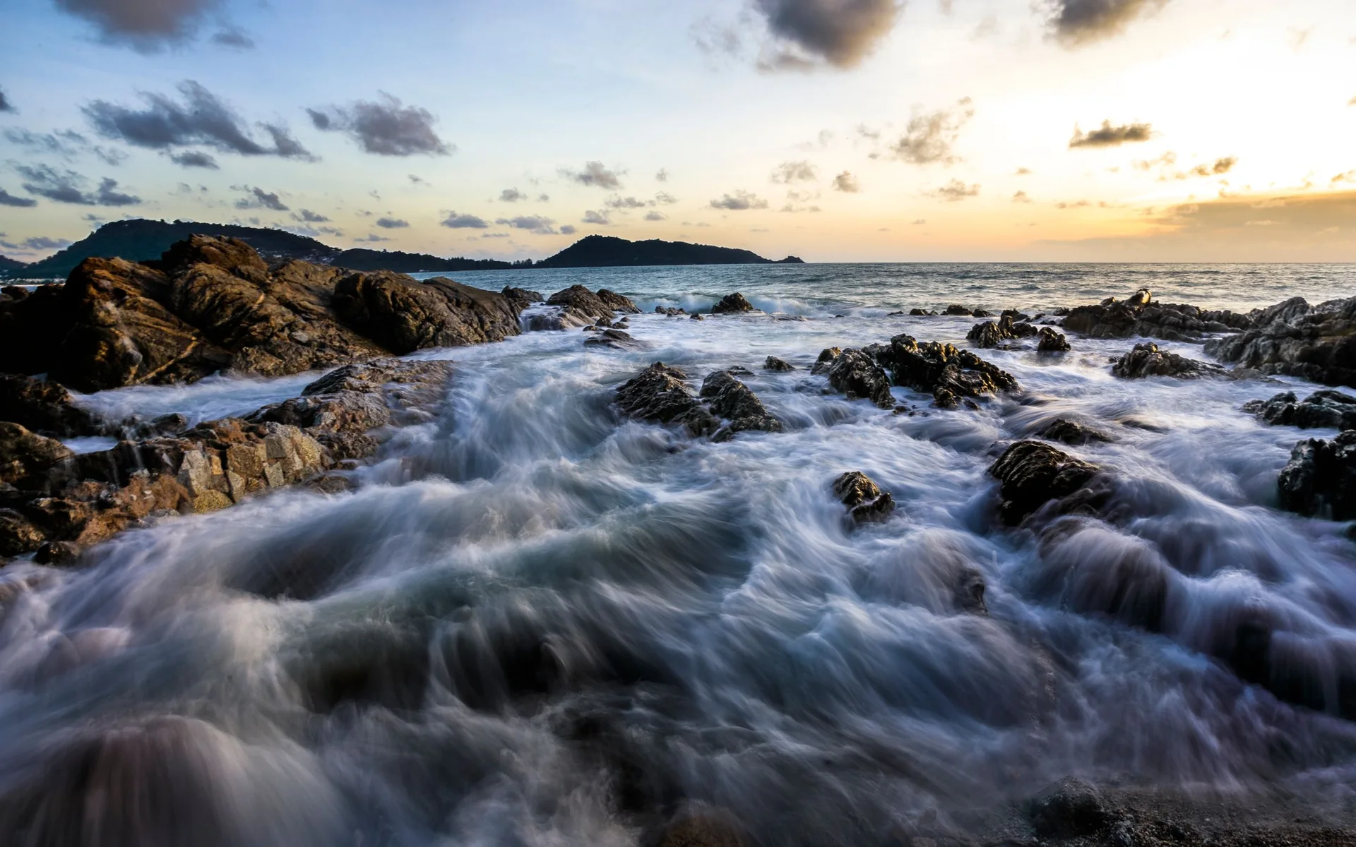 Ondas na costa rochosa de Phuket ao pôr-do-sol