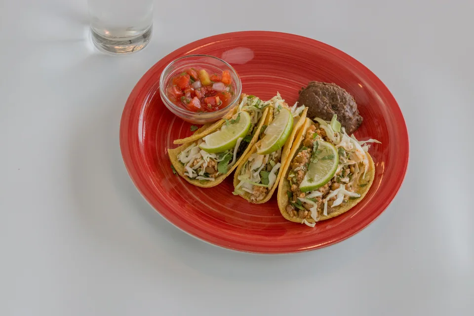 Example photo: Three tacos topped with lime slices, with salsa on a red plate