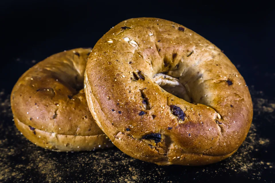 BookNoFees: Fotografia ilustrativa: Dois bagels dourados sobre um fundo escuro